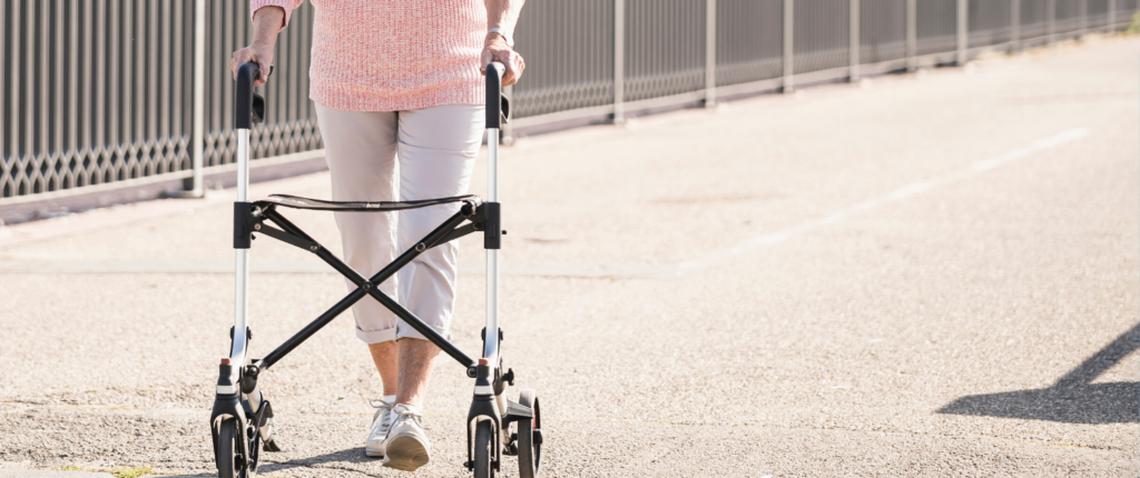Ein Mensch stützt sich beim Gehen auf einen Rollator