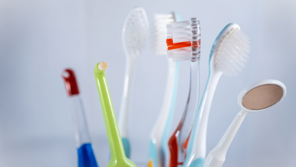 Richtige Mundhygiene: Ein Becher voller Zahn- und Interdentalbürsten vor hellem Hintergrund