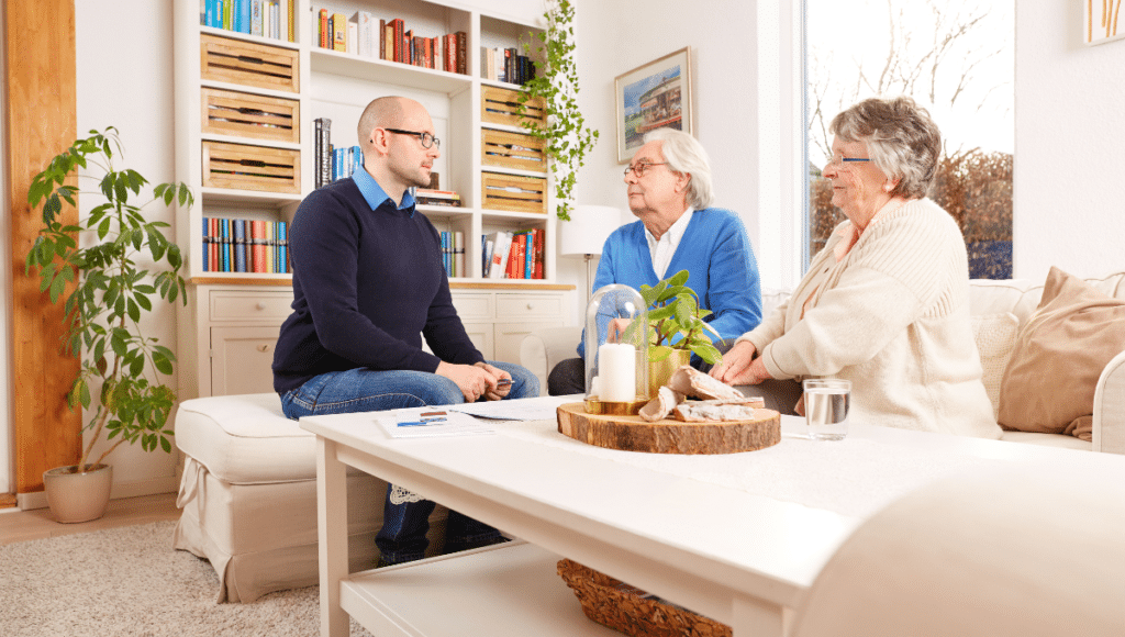 Ein Pflegeberater berät ein älteres Ehepaar zu Hause.