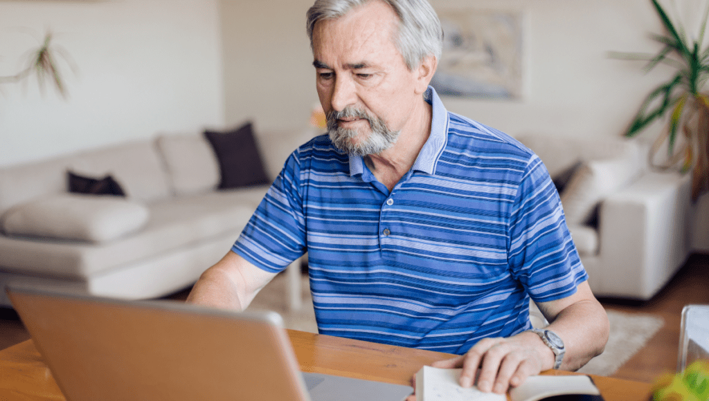 Ein Mann sitzt vor einem Laptop und schreibt einen Widerspruch gegen den erhaltenen Pflegegrad.