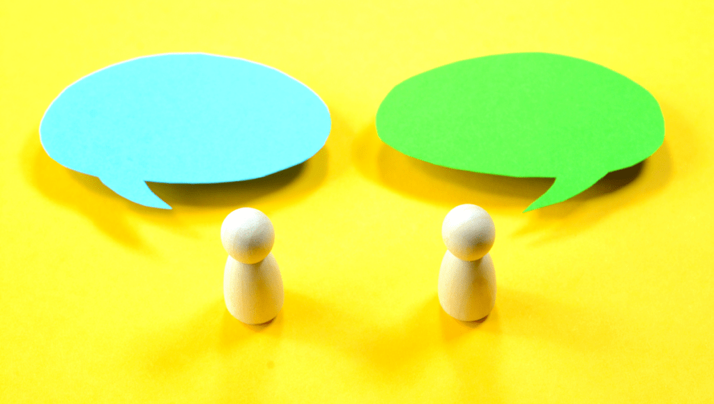 Zwei Holzfiguren mit Sprechblasen