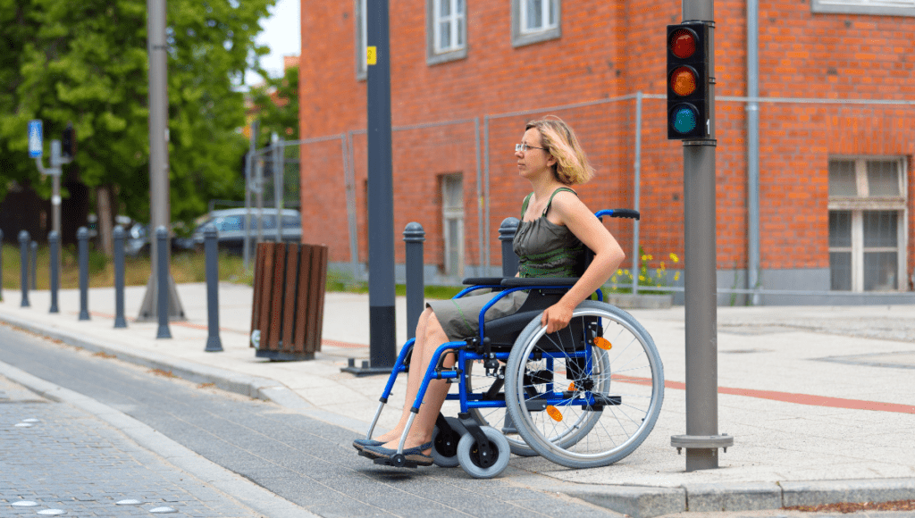 Eine Frau ist mit ihrem Rollstuhl unterwegs und überquert eine Ampel.