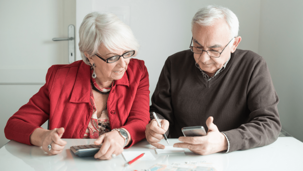 Die Pflegereform 2025 bringt Verbesserungen der finanziellen Leistungen für Pflegebedürftige. Ein Ehepaar sitzt mit Rechner, Handy und Unterlagen an einem Tisch.