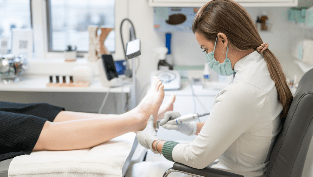 Eine junge Frau führt eine medizinische Fußpflege in einer Praxis durch.