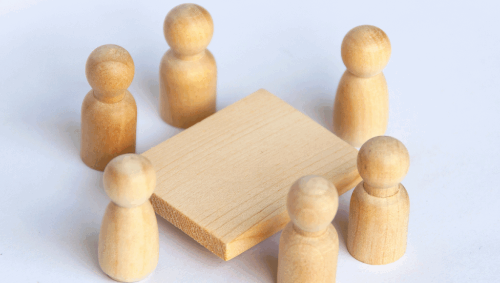 Ein Holztisch, um den herum Holzfiguren stehen.