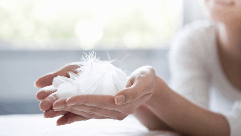 Eine Frau hält weiße Federn in der Hand. Dies soll für Behutsamkeit bei heikler Hygiene stehen.