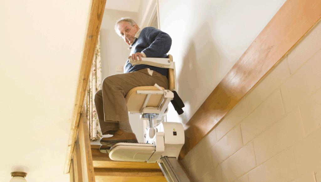 Ein Mann überwindet mit einem Treppenlift die Treppe in seinem Haus.